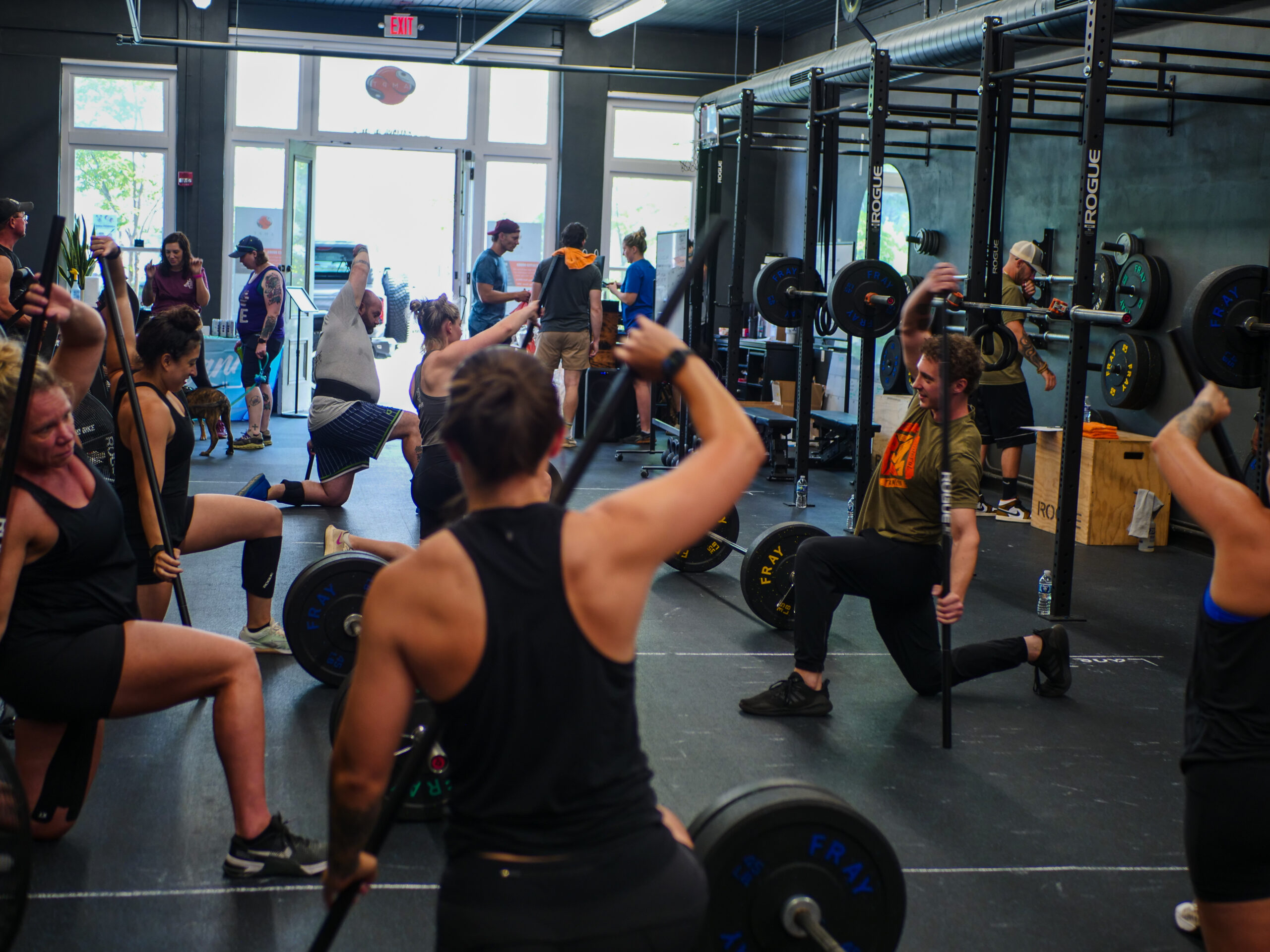 Group of participants engaged in a fitness workshop at AMPT Fit, performing stretching and mobility exercises with equipment. The workshop is led in a structured environment, with attendees focused on improving their movement and technique.